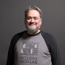 Portrait of Bryce Johnson in a grey and black baseball tee with "Inclusive Tech Lab" and image printed on the front.