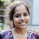Portrait of Lalitha Bandaru in a purple scoop-necked geometric print shirt.