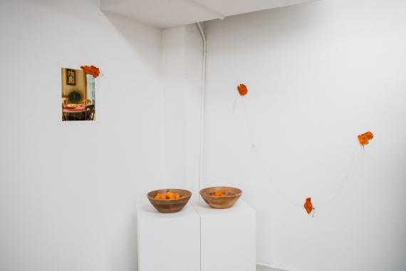Exhibition view of student's work with a photo and two tables below.\