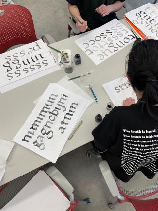 Burke and design instructor practicing calligraphy on paper