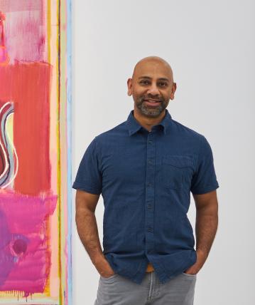 Sangram Majumdar standing in front of one of his paintings.
