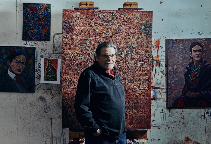 Alfredo Arreguin standing in front of a painting in his studio