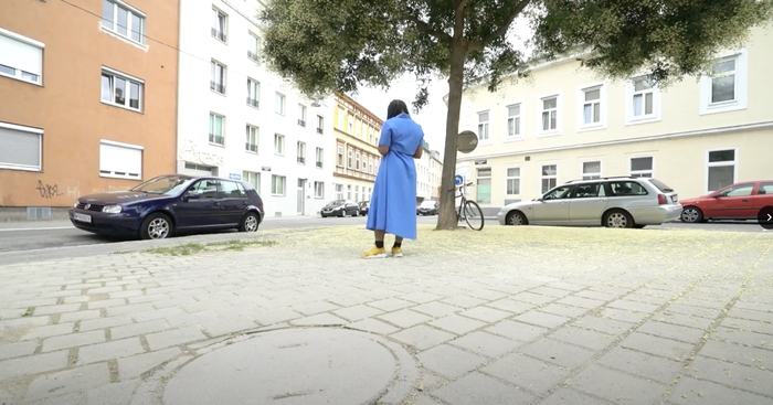 Person in blue dress standing alone in a city plaza