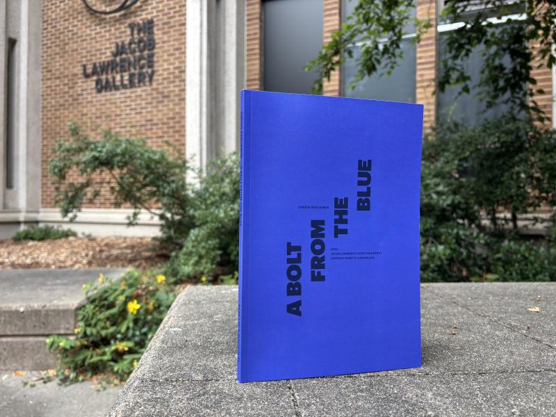 "A Bolt from the Blue" publication with the Jacob Lawrence Gallery in the background