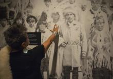 Close-up of exhibition with visitor touching a portrait