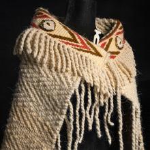 A woven shawl with a decorative band at the neck.