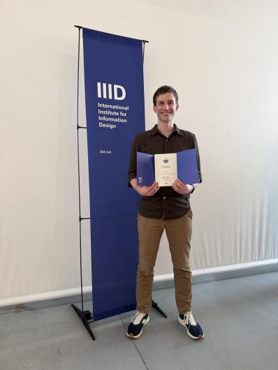 Chad Hall holding an award at the International Institute for Information Design Conference