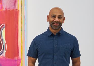 Sangram Majumdar standing in front of one of his paintings.