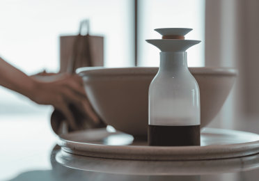 A photo of a bottle next to a bowl on top of a plate.