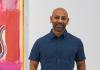 Sangram Majumdar standing in front of one of his paintings.