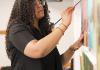 Kyra Wolfenbarger standing and painting in an art studio.