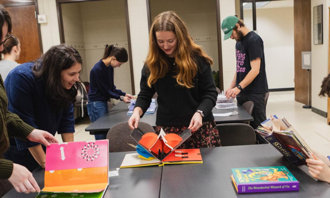 Art history students looking at pop-up books in the UW special collections library. 