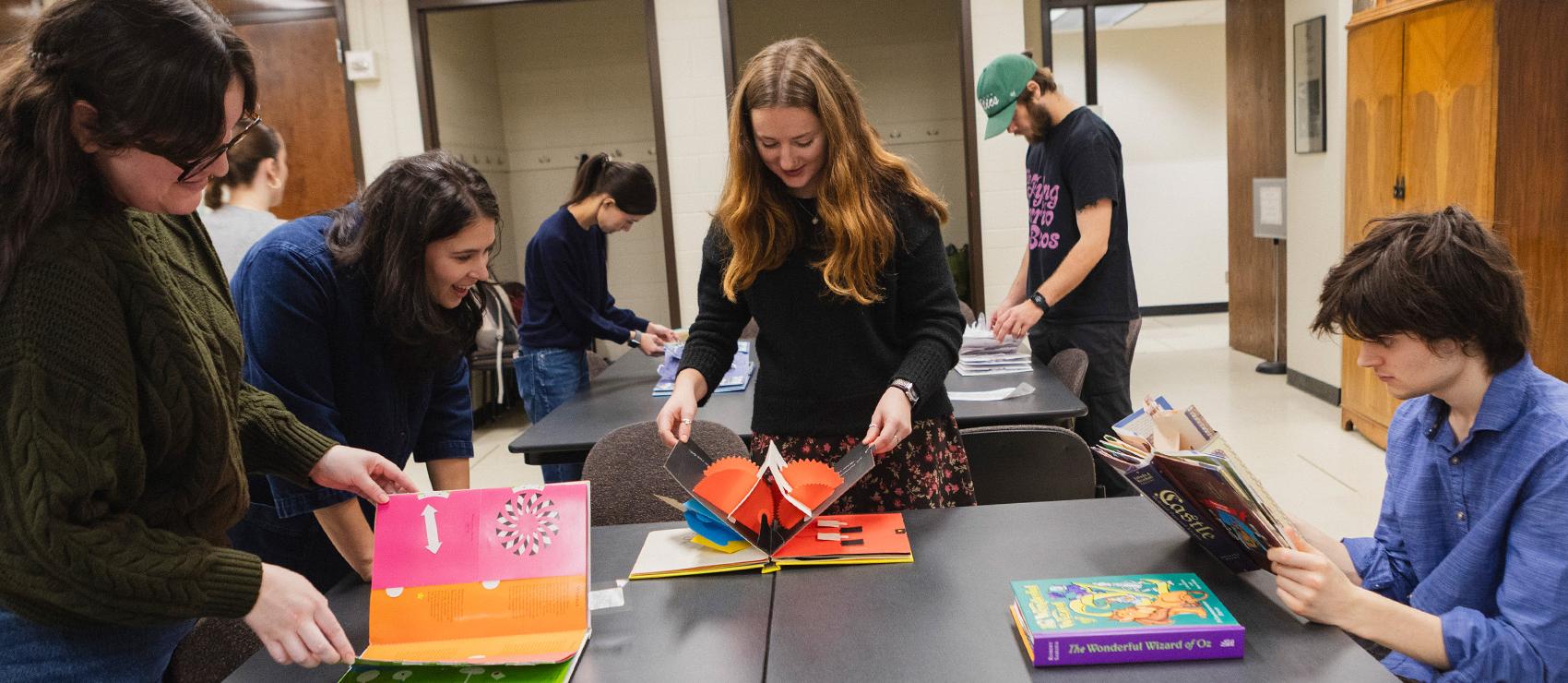 Art history students looking at pop-up books in the UW special collections library. 