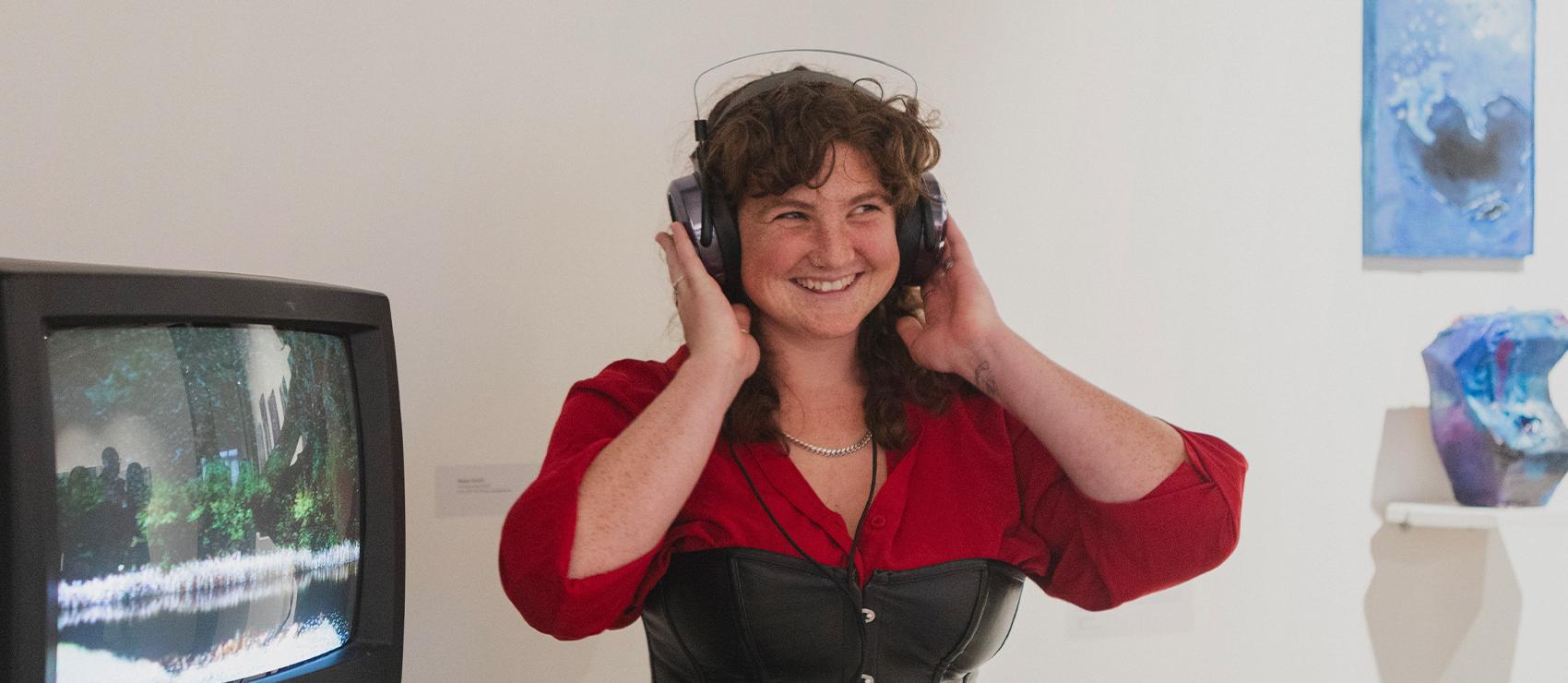 Student smiling with headphones on in the Jacob Lawrence Gallery