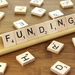 The word "Funding" spelled from Scrabble tiles
