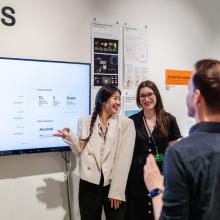Attendees conversing in front of student work on display.
