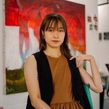 Yongqi Tang sitting down with painting in the background