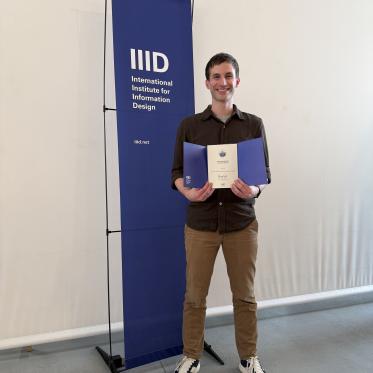 Chad Hall holding an award at the International Institute for Information Design Conference