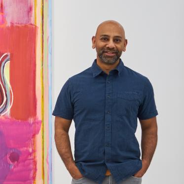 Sangram Majumdar standing in front of one of his paintings.