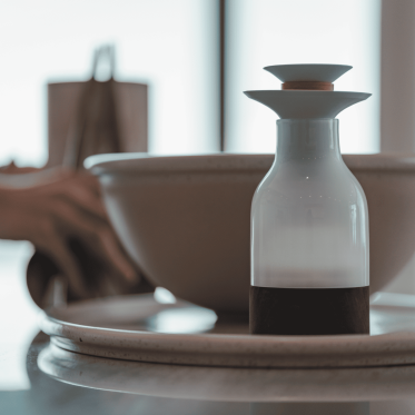 A photo of a bottle next to a bowl on top of a plate.